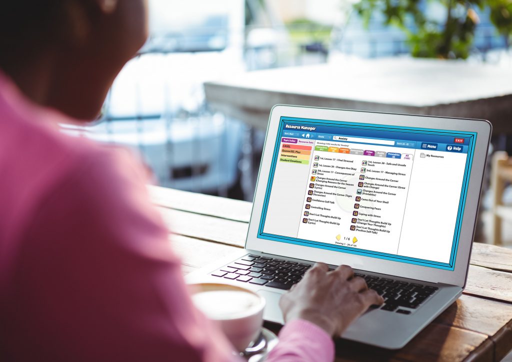 Image of Over the shoulder visual of teacher planning a lesson on social-emotional learning using web-based curriculum resources.