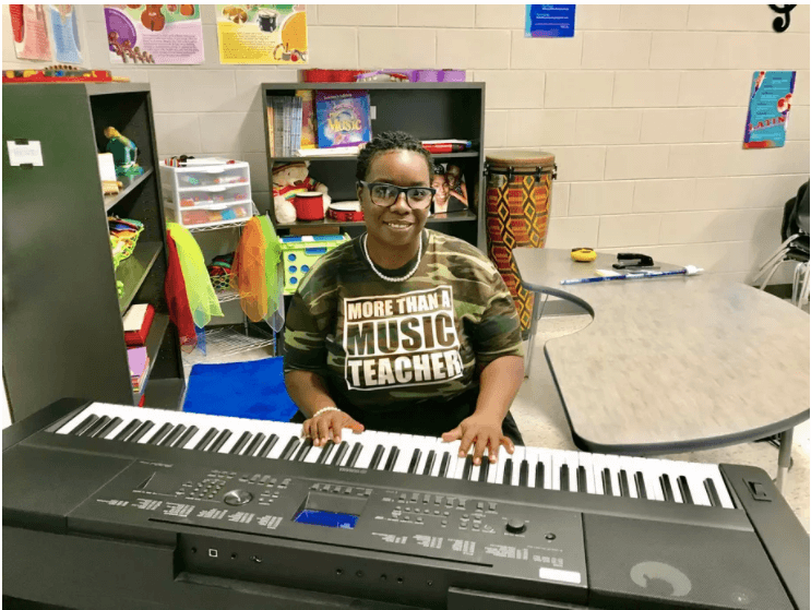 Image of Quaver teacher Alicia Engram sitting at a keyboard in her music classroom