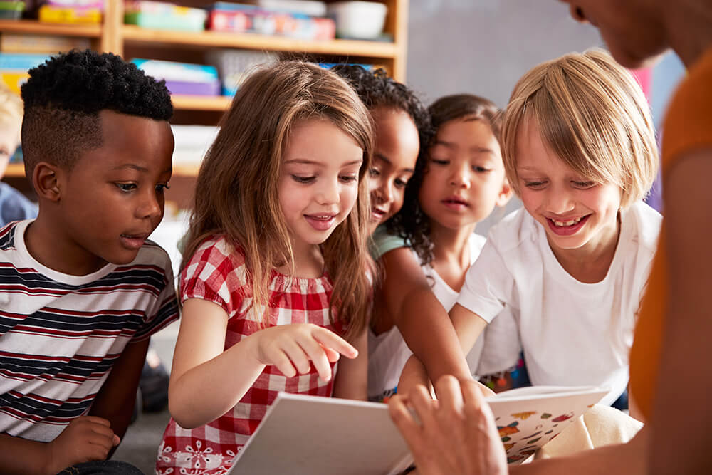 Group of students engage with a book as their teacher reads