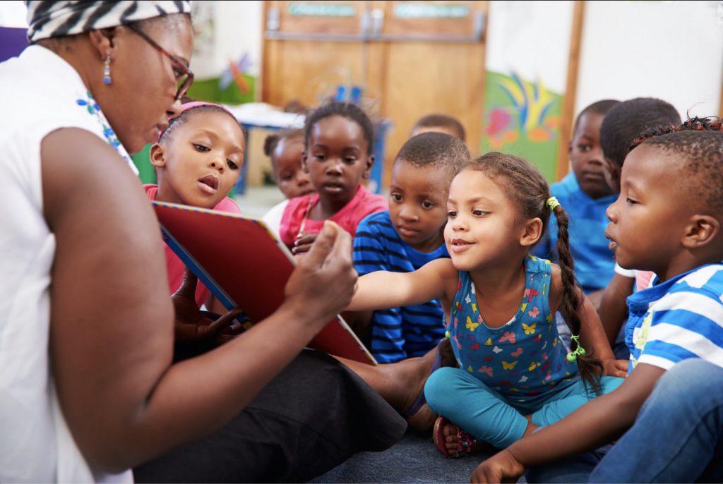 PreK Students Reading with Teacher on the Floor