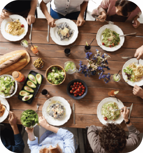 A table of people enjoying a meal from overhead representing the theme Communities from Quaver Pre-K. Curriculum. QuaverEd
