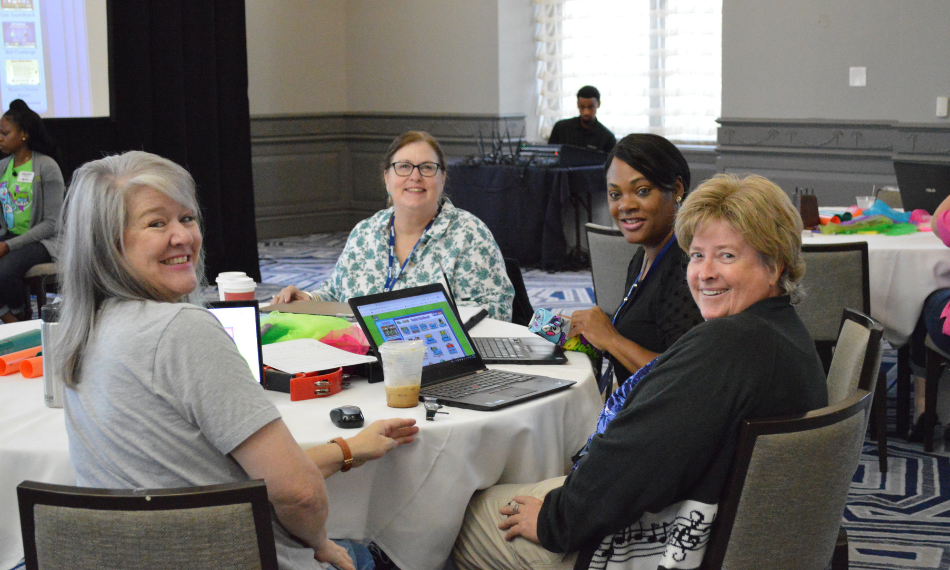 Teachers smiling at the camera while going through Quaver Ready curriculum training at a conference