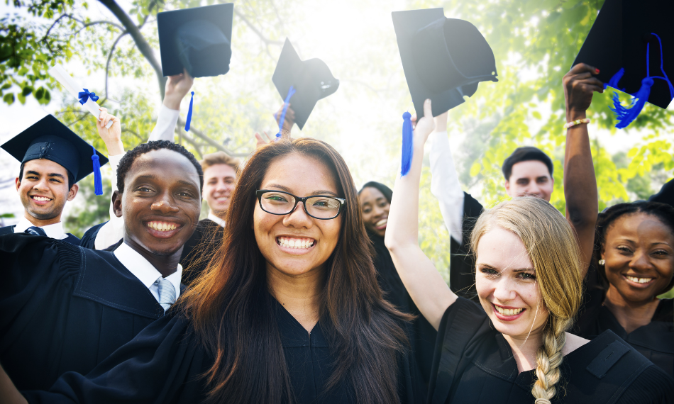 HigherEd-Students-Graduation – QuaverEd A diverse group of college graduates smiling and raising their caps.