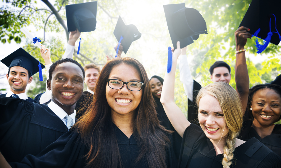 A diverse group of college graduates smiling and raising their caps. 