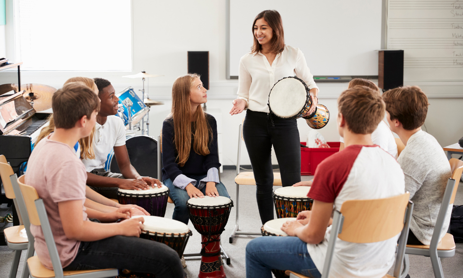 QuaverEd-HigherEd-Students-With-Instruments – QuaverEd A diverse group of young adults playing drums.