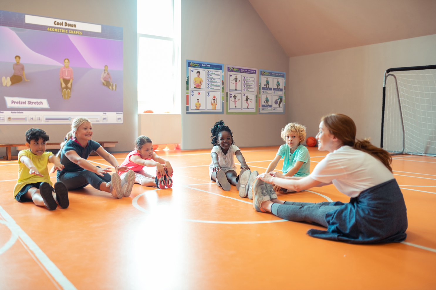 A Quaver Health and PE teacher leading her students in a stretching exercise in a gym