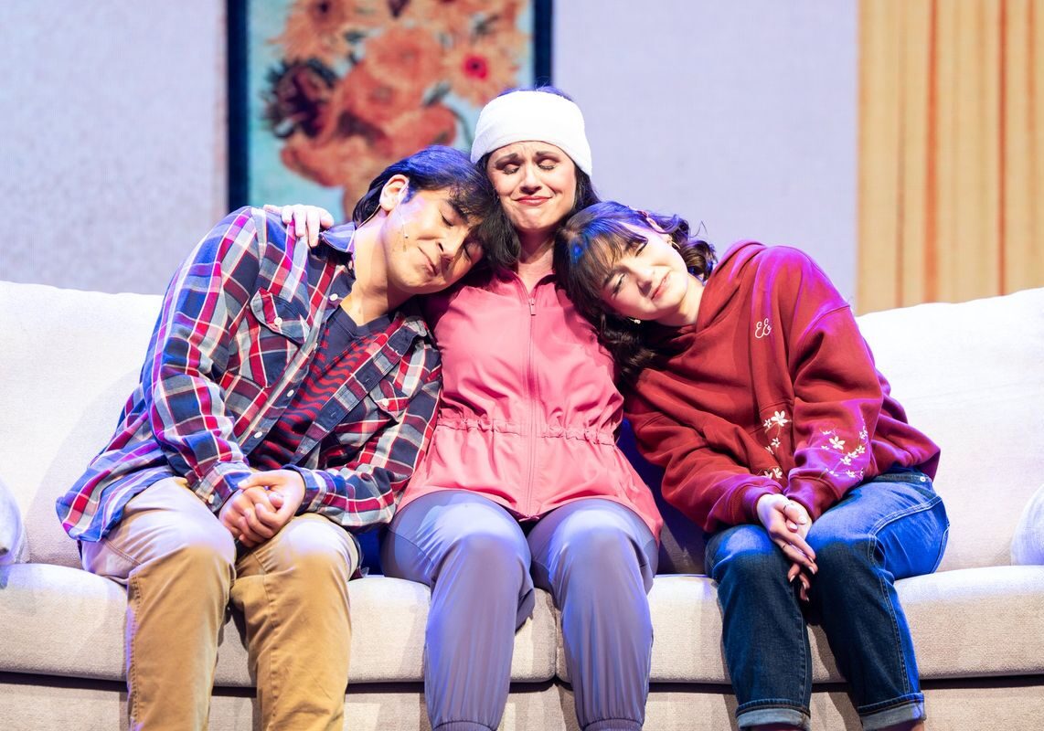 A mother sits on a couch with her son and daughter