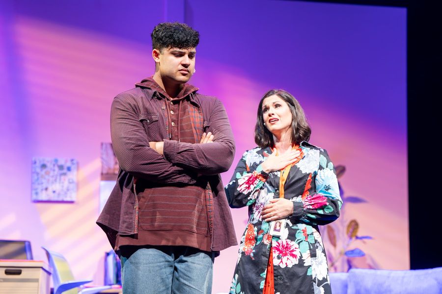 A school counselor speaks to a student who stands with his arms crossed