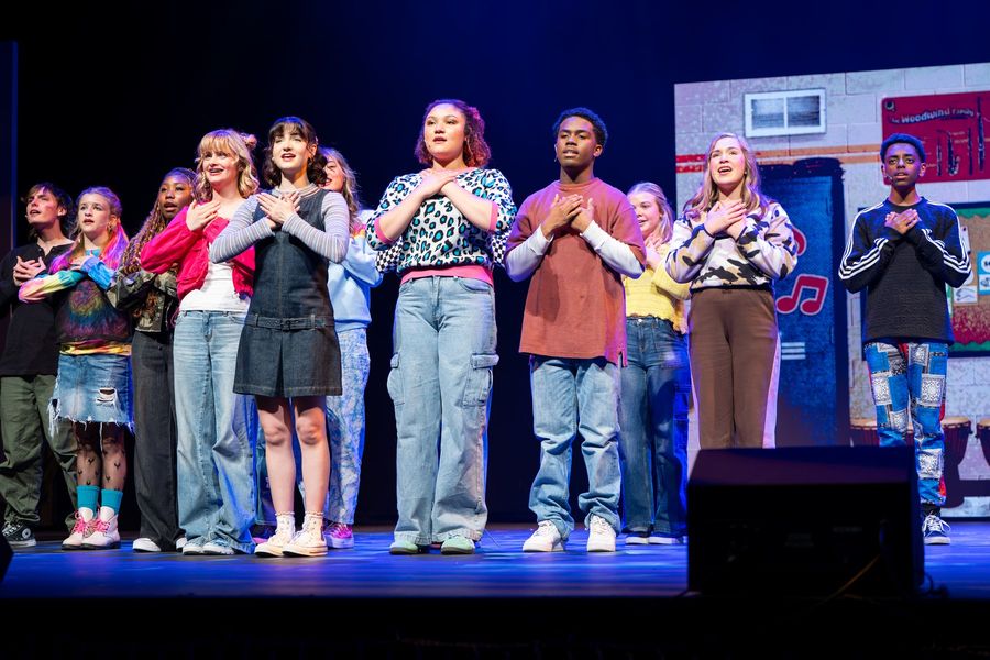 Students sing with their hands over their hearts
